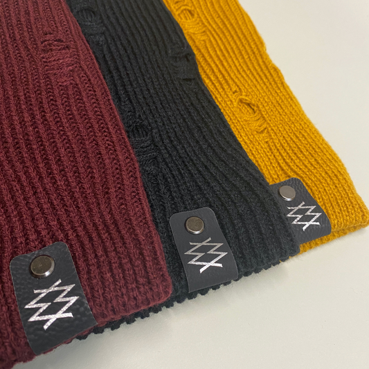 Three layered beanies in black, mustard and burgundy each showcasing the DUUW WUUD logo on the edge.