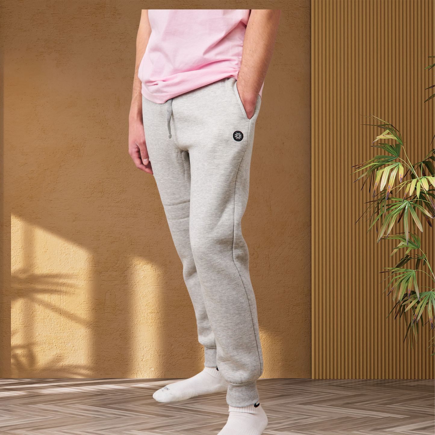 Man wearing gray fleece jogger sweatpants with ribbed bottom cuffs. The joggers have a tapered slim fit and a drawstring waistband. Sweatpants showcasing DUUW WUUD logo on the side. 